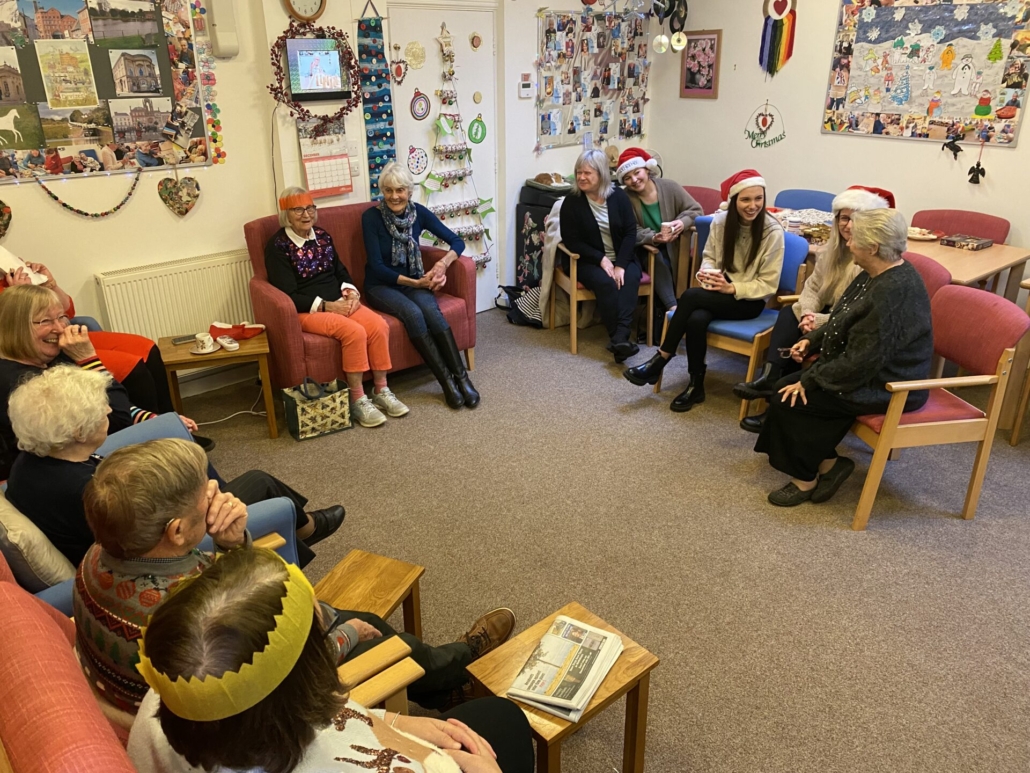 Alzheimer's Support Members and Quickmove team sat in a circle on chairs chatting and laughing together