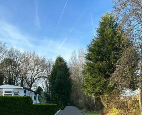 Surroundings of residential park home site in Manchester with trees and blue sky